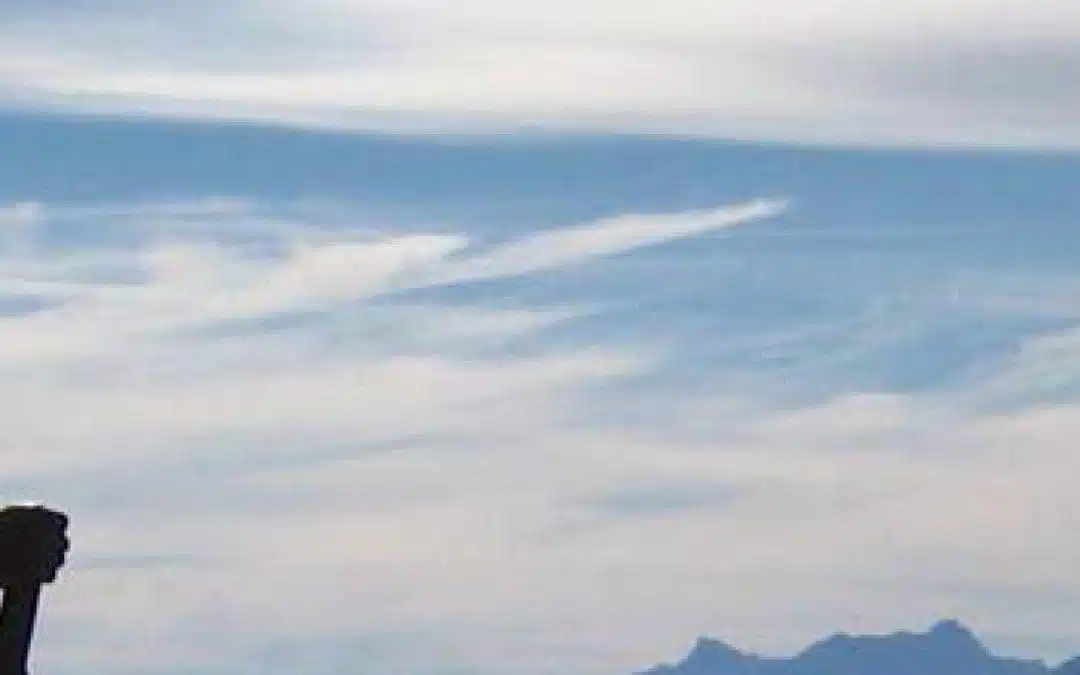 Hiker silhoutted against a blue sky with wispy clouds