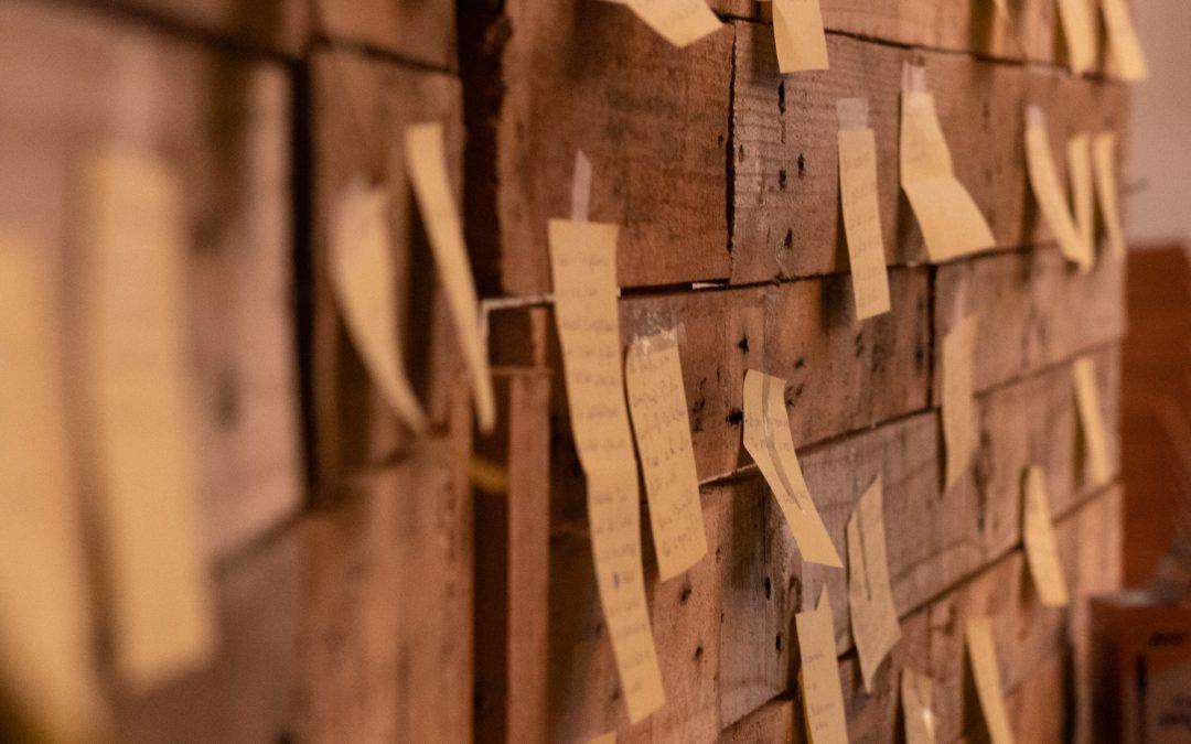 Rustic wooden wall with a myriad of little notes taped to it